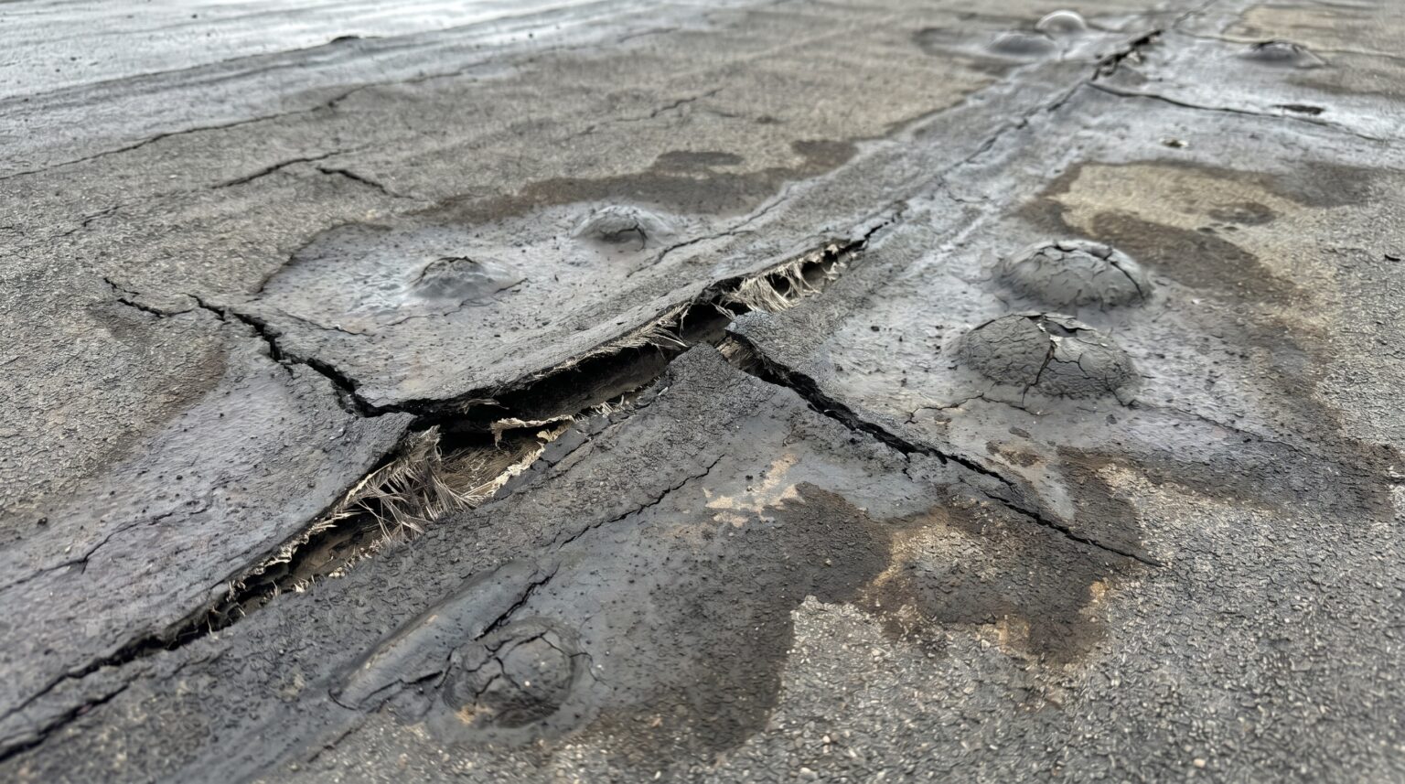 Rissige Bitumen-Abdichtung mit Blasen und aufgeplatzter Naht auf einem Flachdach