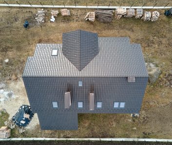 Aerial view of house roof top covered with ceramic shingles. Tiled covering of building under construction.