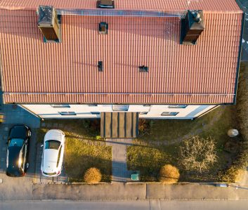 Aerial view of residential houses with red roofs and streets with parked cars in rural town area. Quiet suburbs of a modern european city.