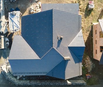 Chimney on house roof top covered with metallic shingles under construction. Tiled covering of building. Real estate development Chimney on house roof top covered with metallic shingles under construction. Tiled covering of building. Real estate development.