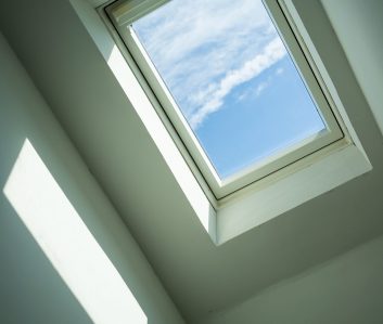 Closed roof window through which you can see the blue sky and white clouds on a sunny day. Bottom view. Closed roof window through which you can see the blue sky and white clouds on a sunny day. Modern technologies. Bottom view.