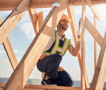 joyous-construction-site-worker-with-hammer-building-a-roof-carcass-1024x682-1.jpg
