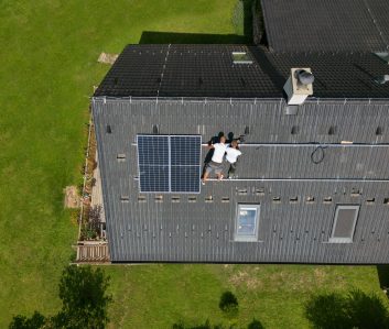 Men worker installing solar photovoltaic panels on a roof, alternative energy, saving resources and sustainable lifestyle concept.