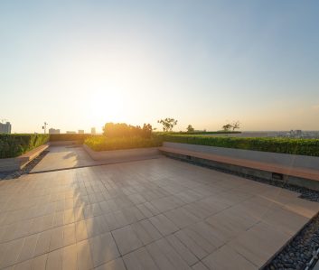 Sky garden on private rooftop of condominium or hotel, high rise architecture building with tree, grass field, and blue sky.